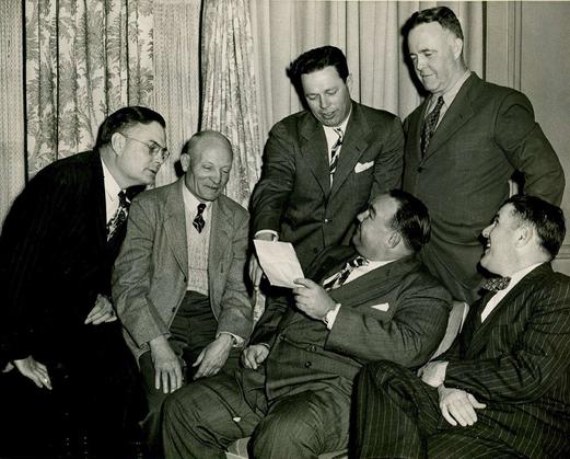 A group of men in suits and ties sitting around each other.