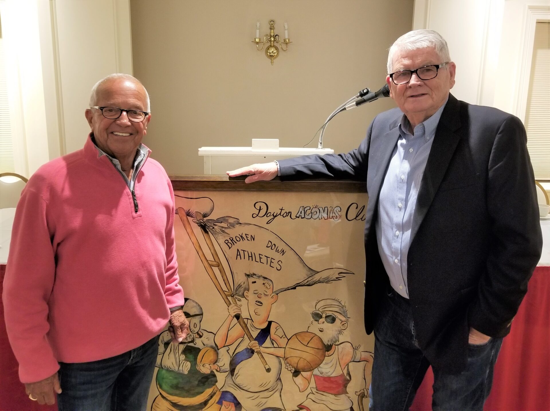 Two men standing next to a painting of cartoon characters.